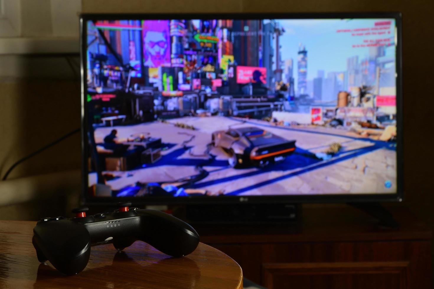 KHARKOV, UKRAINE - NOVEMBER 12, 2020 Video game controller Gamesir g3s on table with Cyberpunk 2077 game on display photo