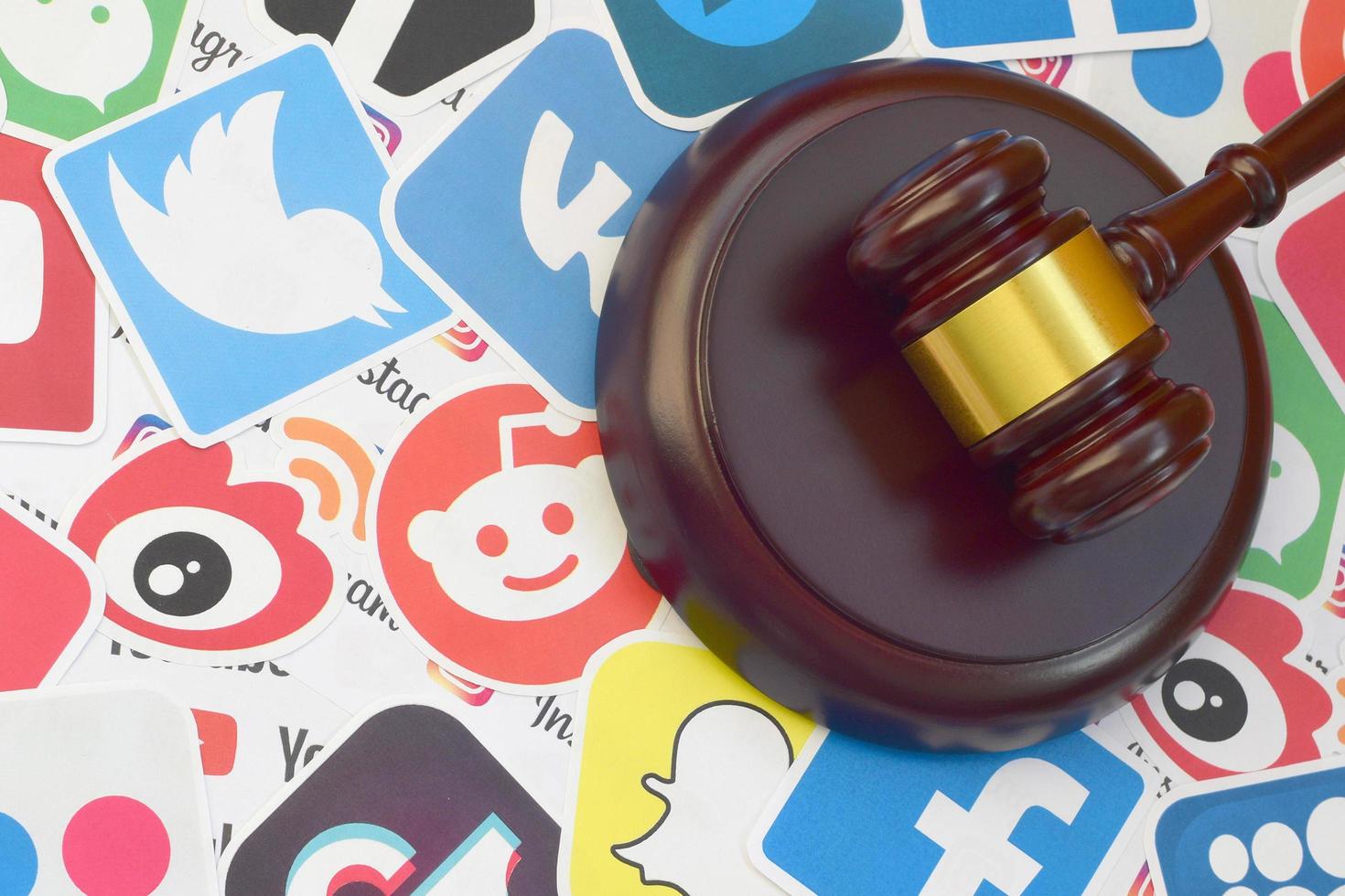 Wooden judge gavel lies on many paper logos of popular social networks and internet resources. Entertainment lawsuit concept photo