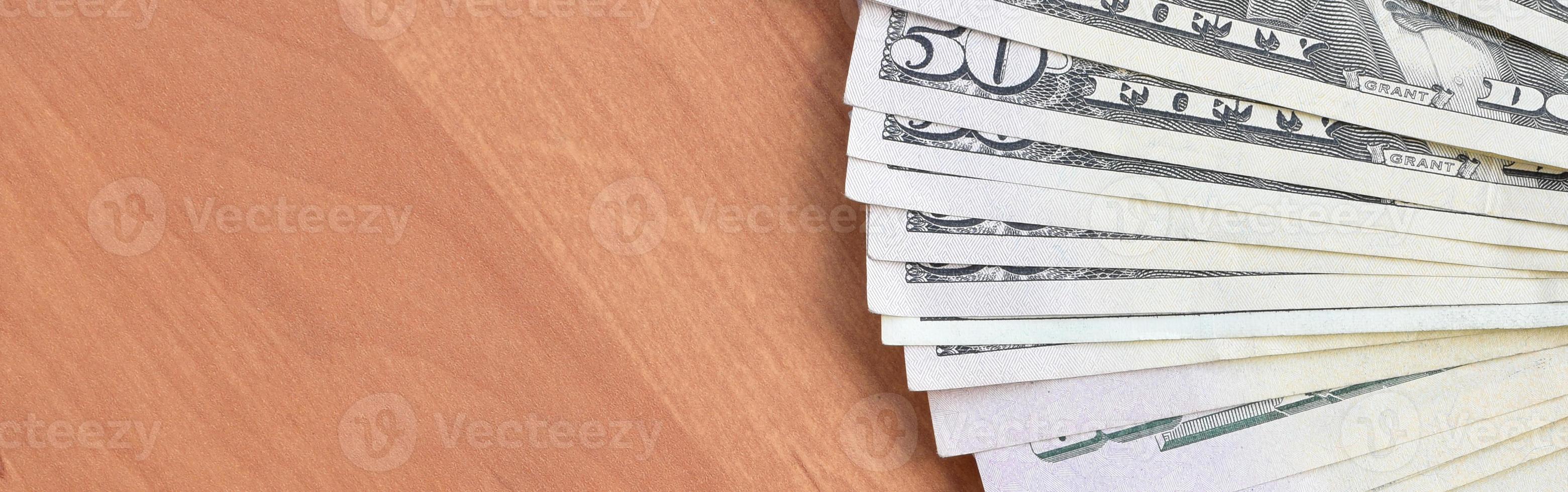 Fan of many one hundred and fifty dollar bills on wooden background surface close up. Flat lay top view. Abstract business concept photo