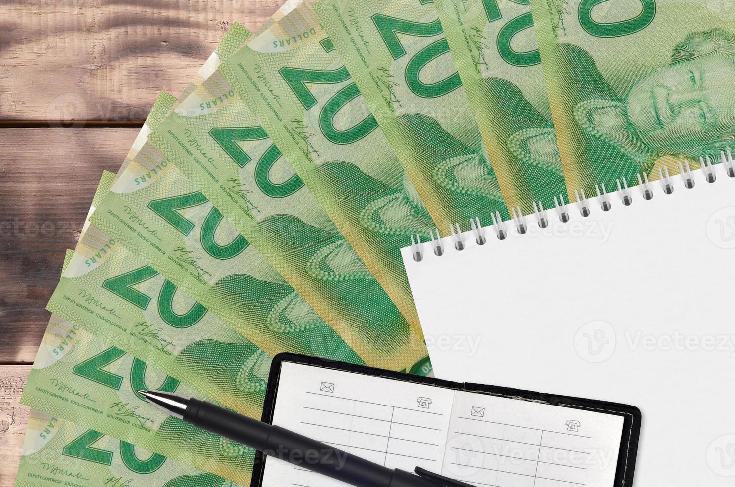 20 Canadian dollars bills fan and notepad with contact book and black pen. Concept of financial planning and business strategy photo
