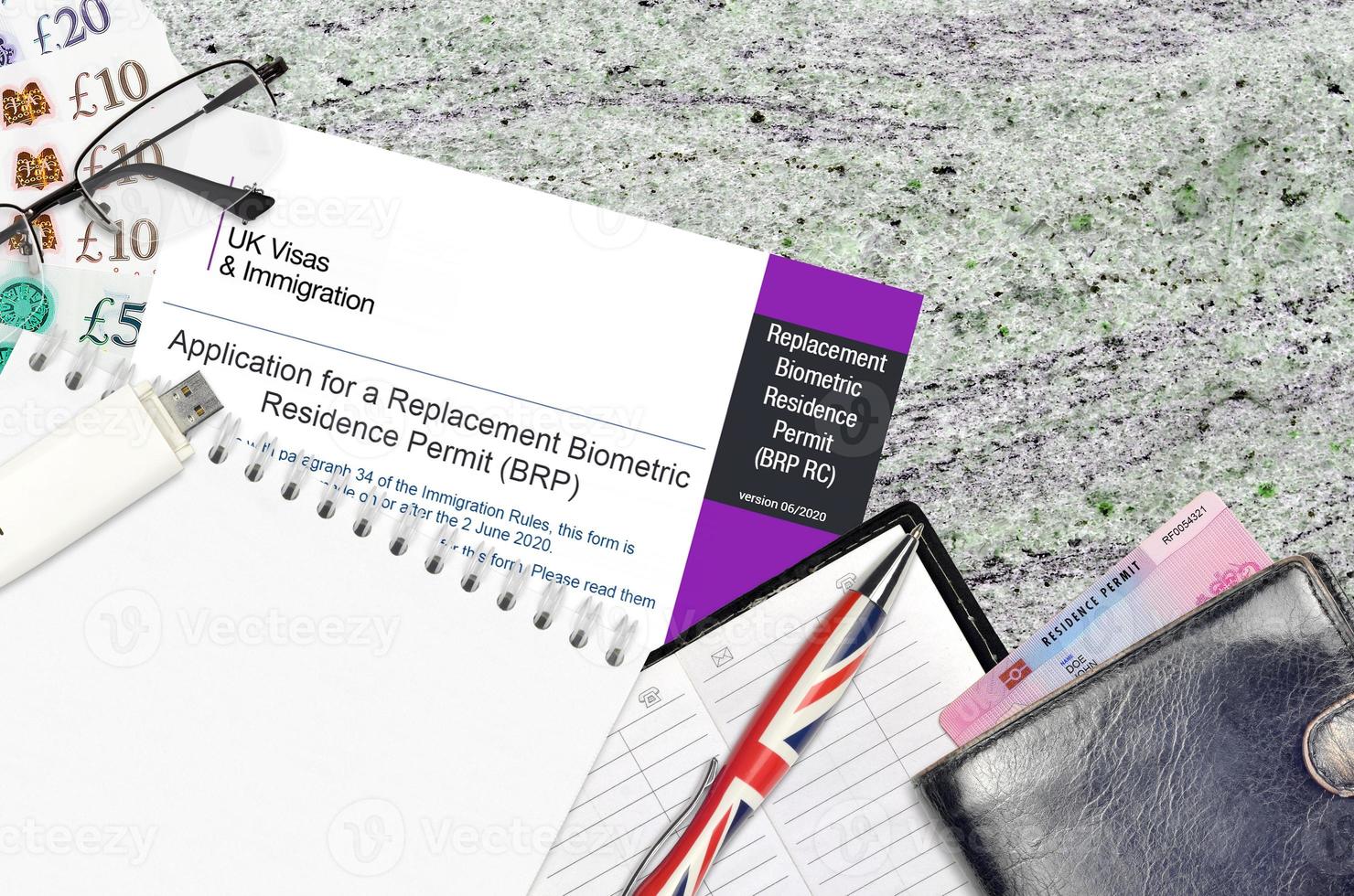 English form BRP RC Application for a replacement biometric residence permit card from UK visas and immigration services lies on table with office items. UK residence permit paperwork photo