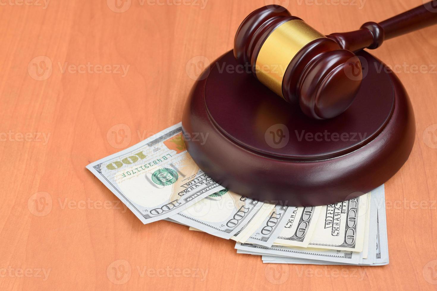 Judge gavel and money on brown wooden table. Many hundred dollar bills under judge malice on court desk. Judgement and bribe photo