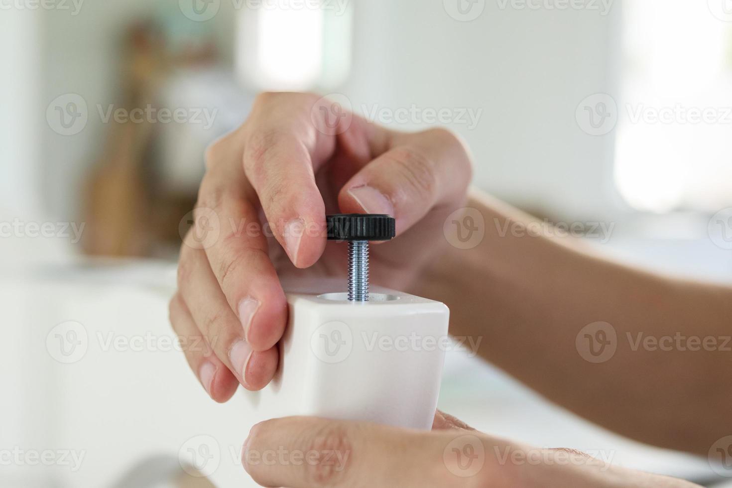 Asian man assembling furniture at home with adjustable table leg photo