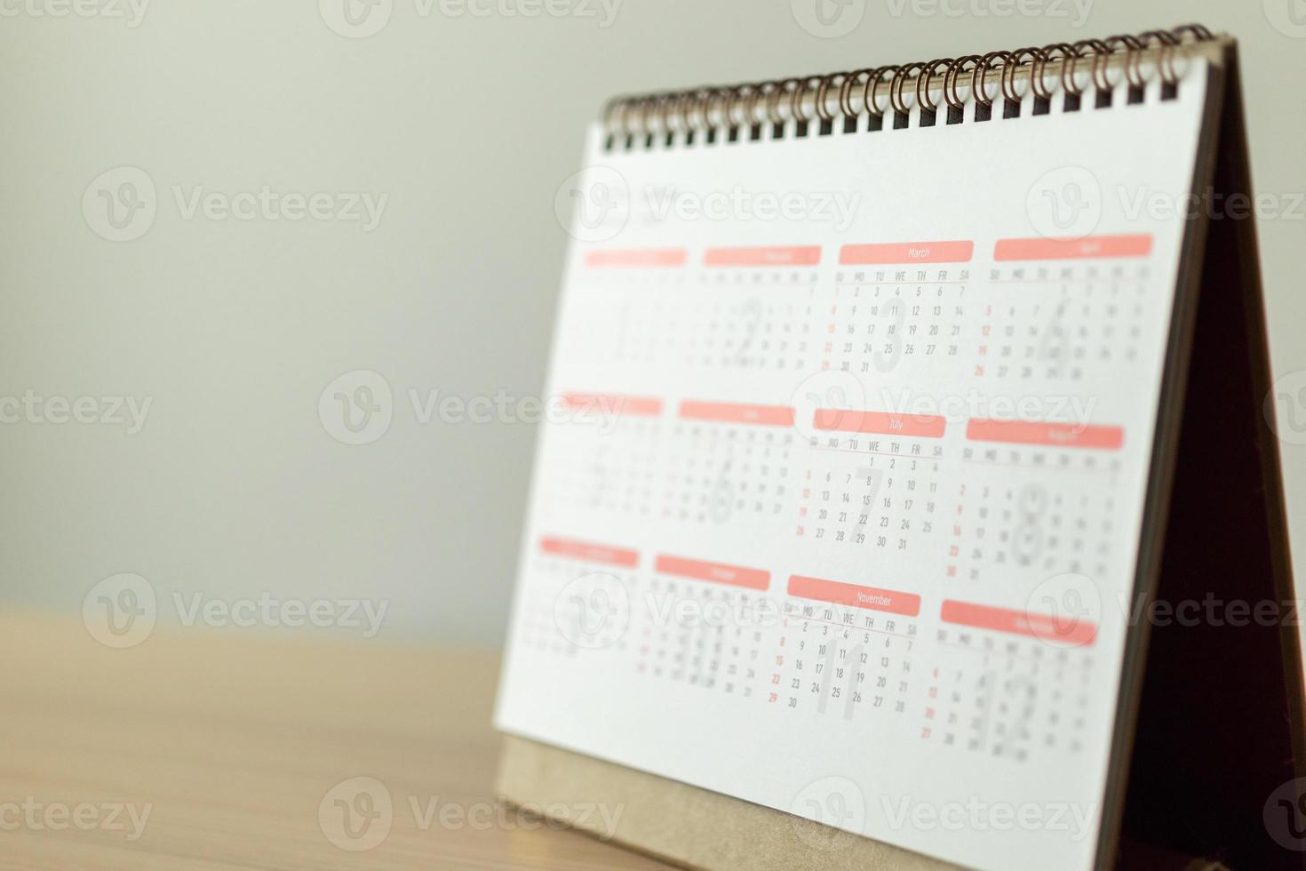 página del calendario de cerca en la mesa de madera con fondo de pared blanca concepto de reunión de cita de planificación empresarial foto