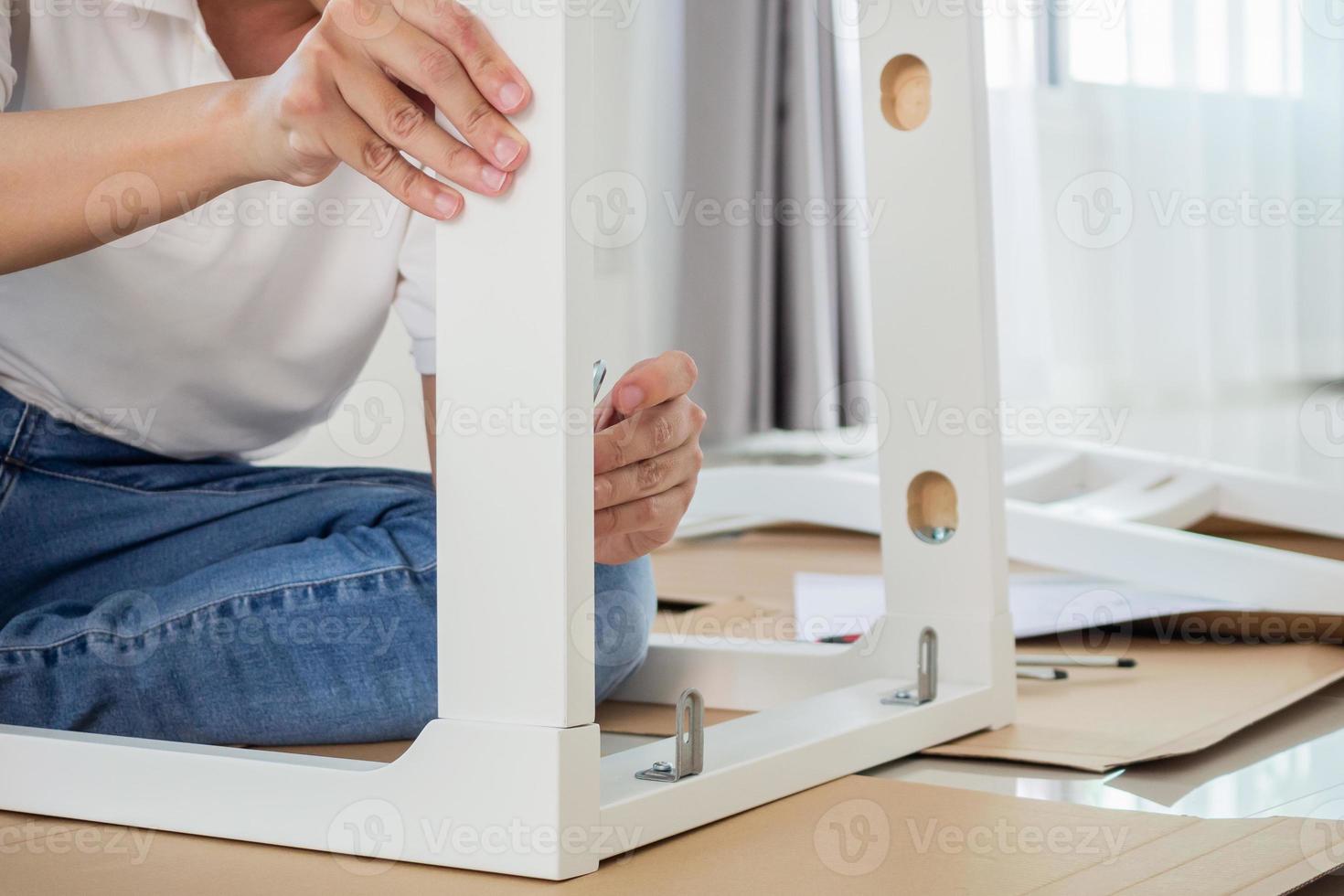 Man assembling white chair furniture at home photo