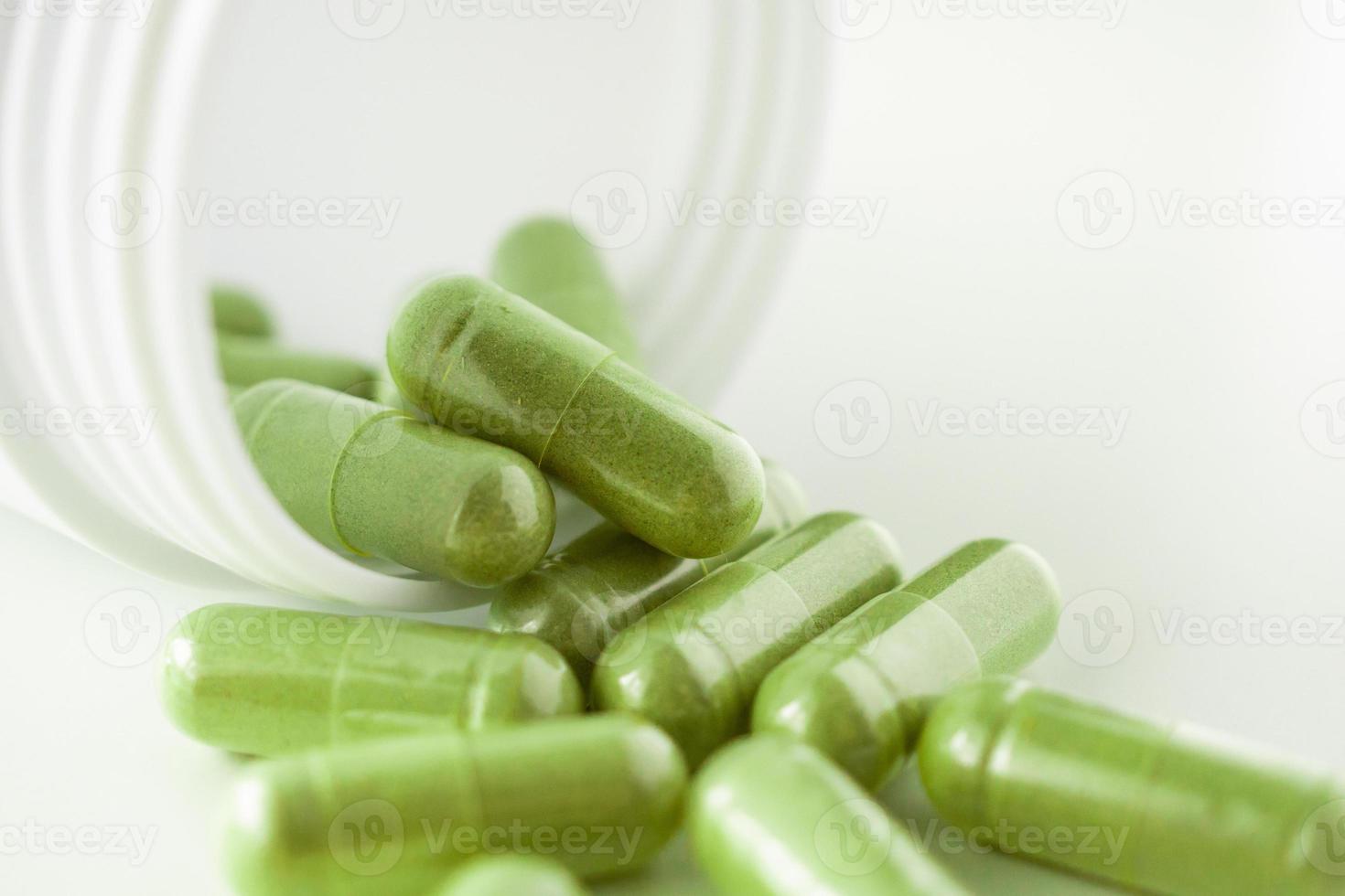 Herbal medicine capsules with bottle on white background photo