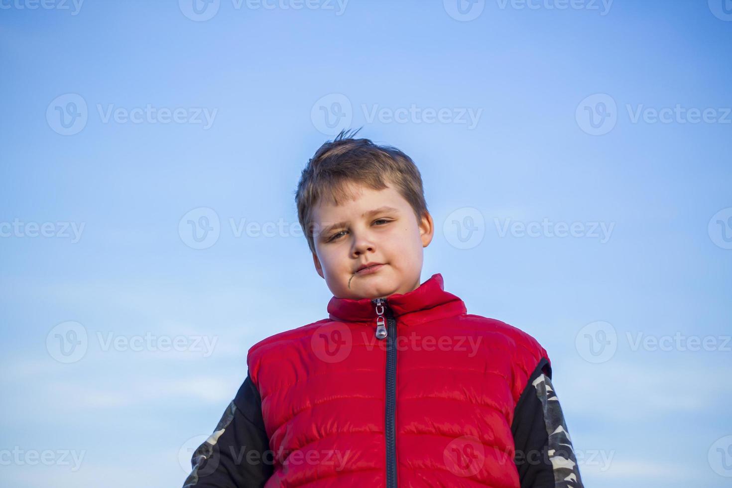 retrato de un niño contra un cielo azul. vista desde abajo. foto