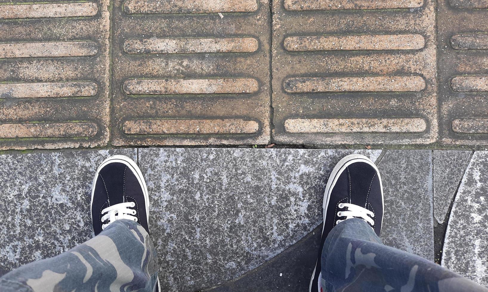 A pair of black shoes with army pants on the side of the road photo