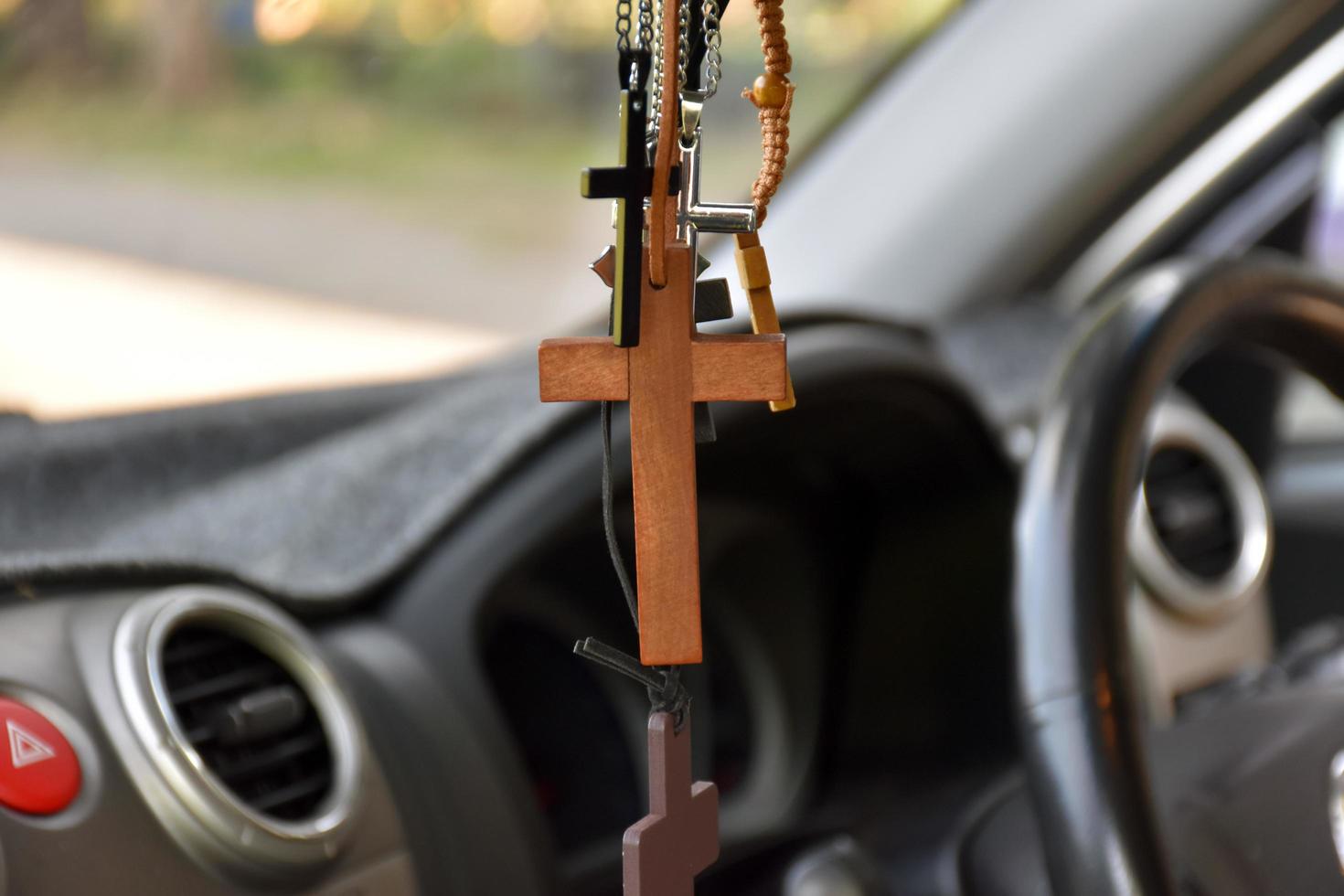 collares de varias formas de cruces se cuelgan en el espejo retrovisor en la consola delantera del automóvil como un talismán para prevenir accidentes durante la conducción. foto