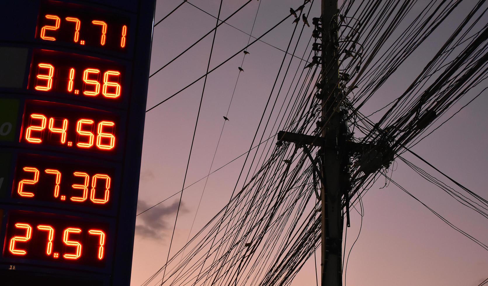 Digital petrol price sign near the electricity pole which has cordage and wirring telephone lines in urban of Thailand. photo