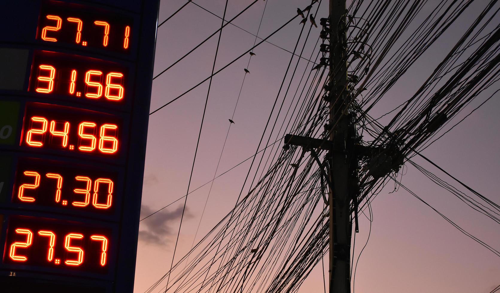 Digital petrol price sign near the electricity pole which has cordage and wirring telephone lines in urban of Thailand. photo