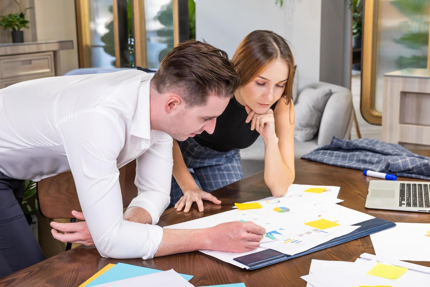 Two adult Caucasian men and women business people having discussion and brainstorm an idea while writing note on document and paper on working table inside of office work space. Teamwork concept. photo