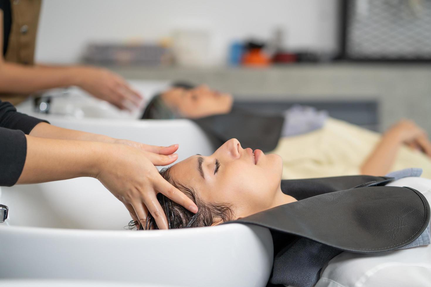 Beautiful Caucasian women feel relax and comfortable while getting hair wash with shampoo and massage. Hair salon studio with hair stylish, beauty and fashion concept. photo