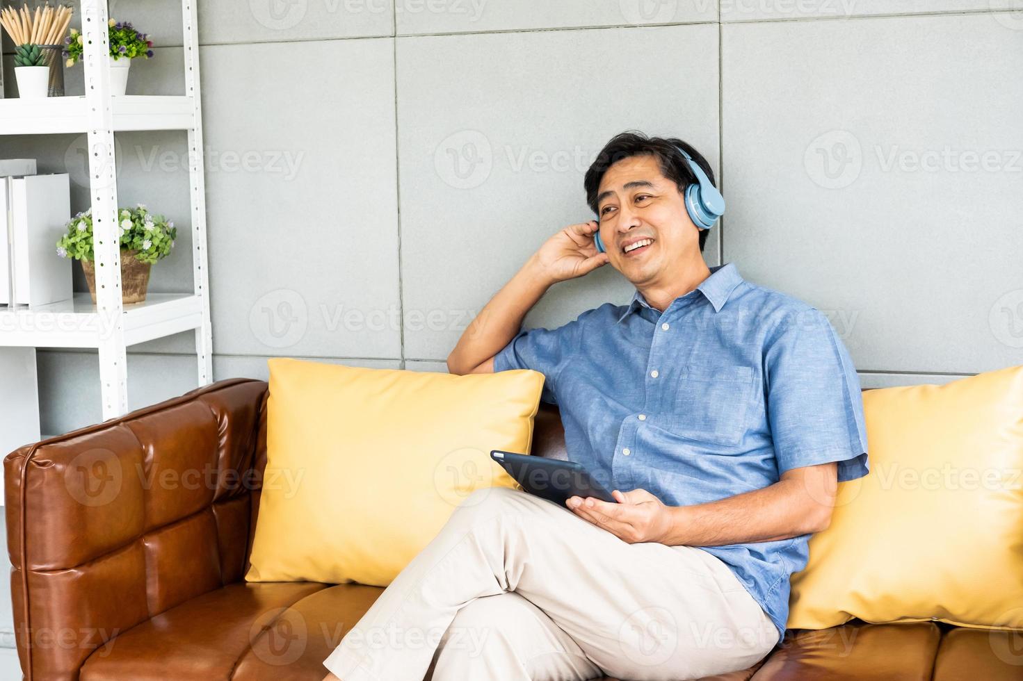 Senior Asian grandfather enjoy and feeling happy while listening music from wireless headphone that streaming music from smartphone or tablet device. Elderly retirement lifestyle with good health. photo