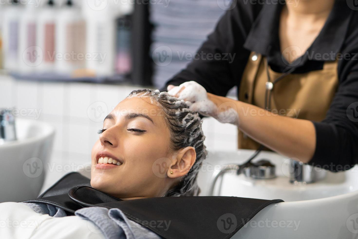 Beautiful Caucasian women feel relax and comfortable while getting hair wash with shampoo and massage. Hair salon studio with hair stylish, beauty and fashion concept. photo