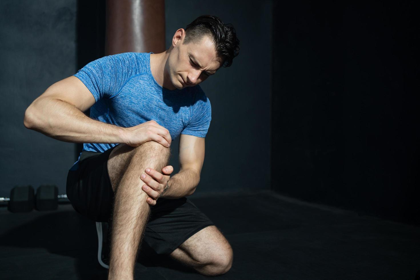 Young adult Caucasian men feeling painful from knee muscle injury after workout with weight lifting, Muscle injured from workout or exercise for weight training. photo