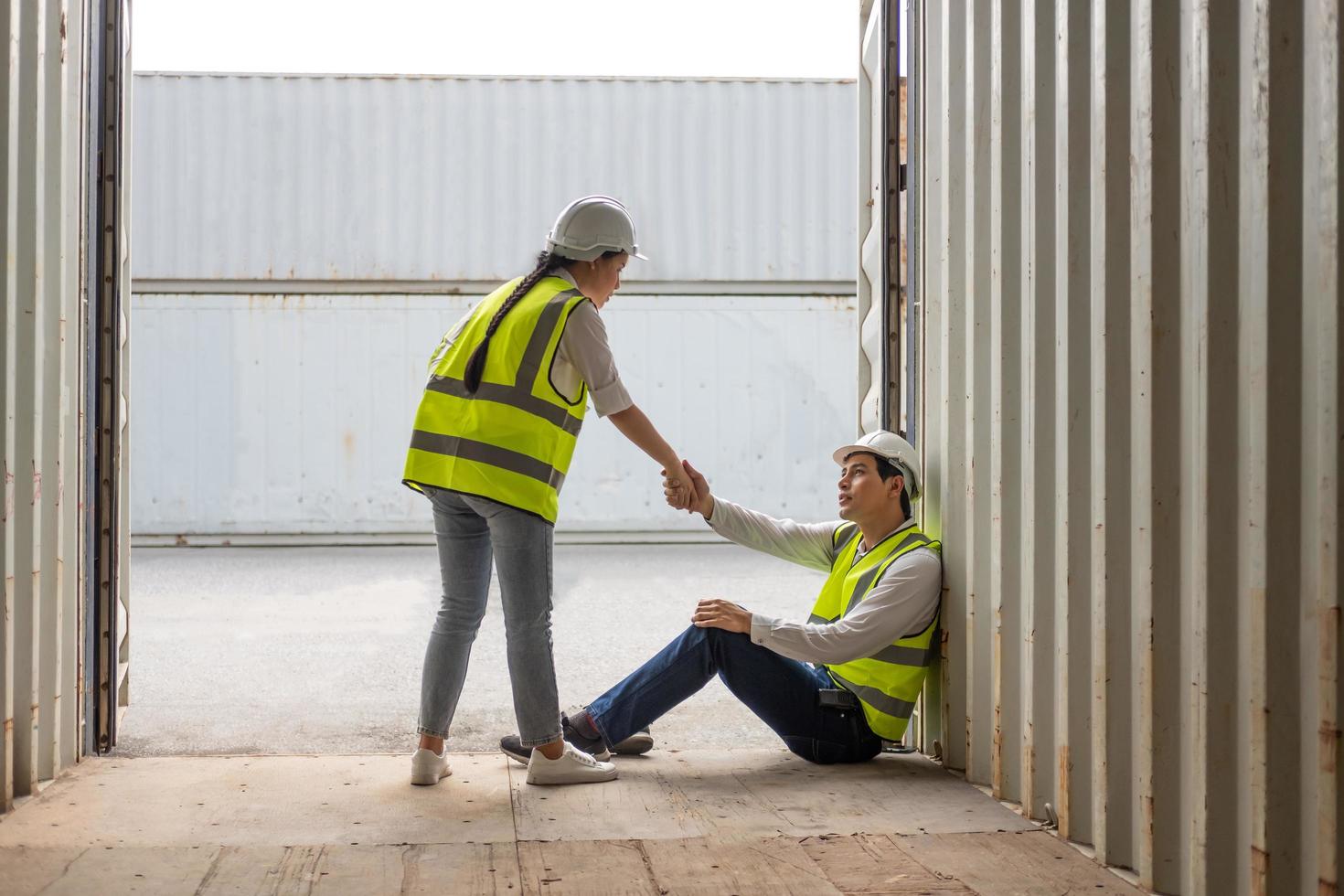 Young adult men and women industrial worker holding hand, encourage and cheer up after hard working day at container transportation import or export site. Teamwork and friendship workplace concept. photo