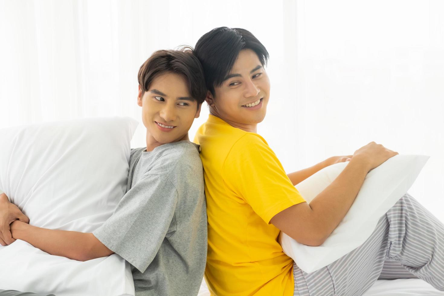 Selective focus at face. Handsome young Asian gay homosexual couple. Hug and embrace on the bed. With rainbow flag as LGBT sign. Gender equality and right. Romantic moment, same sex relationship. photo