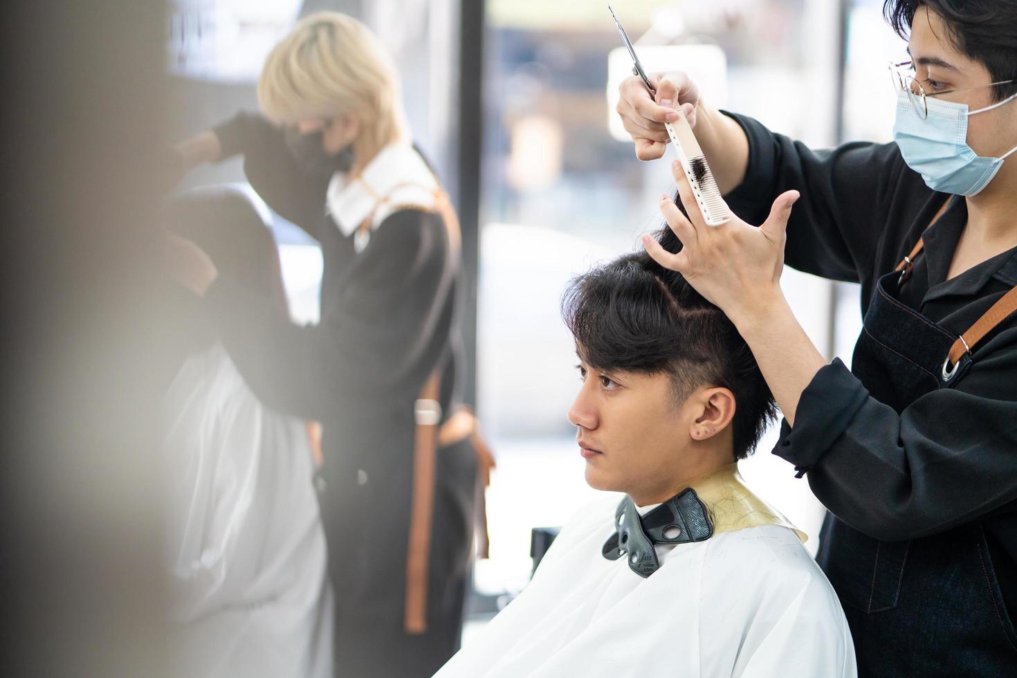 Asian men Hair stylish with customer while do hair cut and wearing surgical  face mask while styling hair for client. Professional occupation, beauty  and fashion service new normal 13000480 Stock Photo at