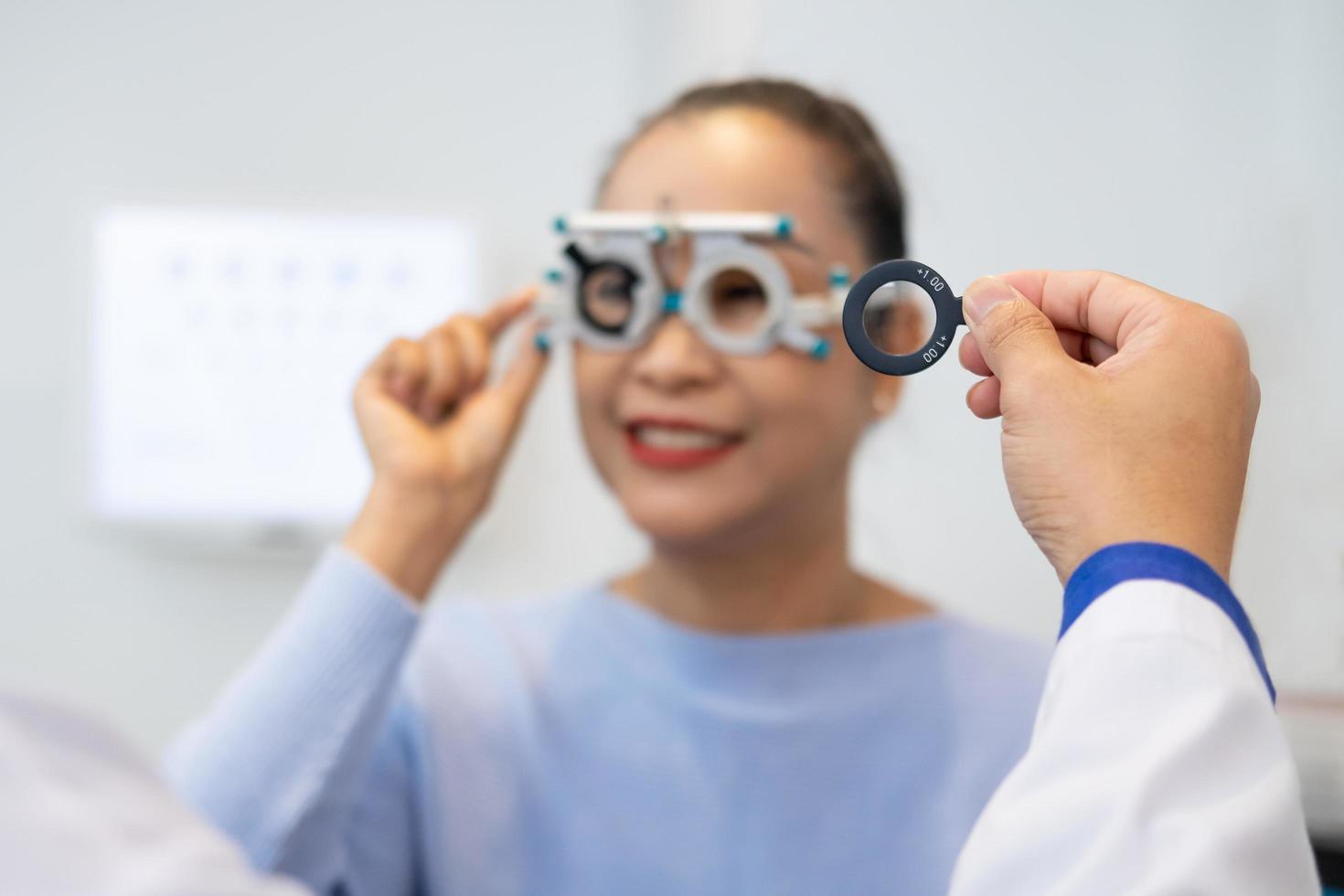 enfoque selectivo en la cara de las mujeres. mientras que el médico usa equipo de optometría y marco de anteojos de prueba para examinar el sistema visual de las mujeres mayores con máquina y técnica profesional. foto