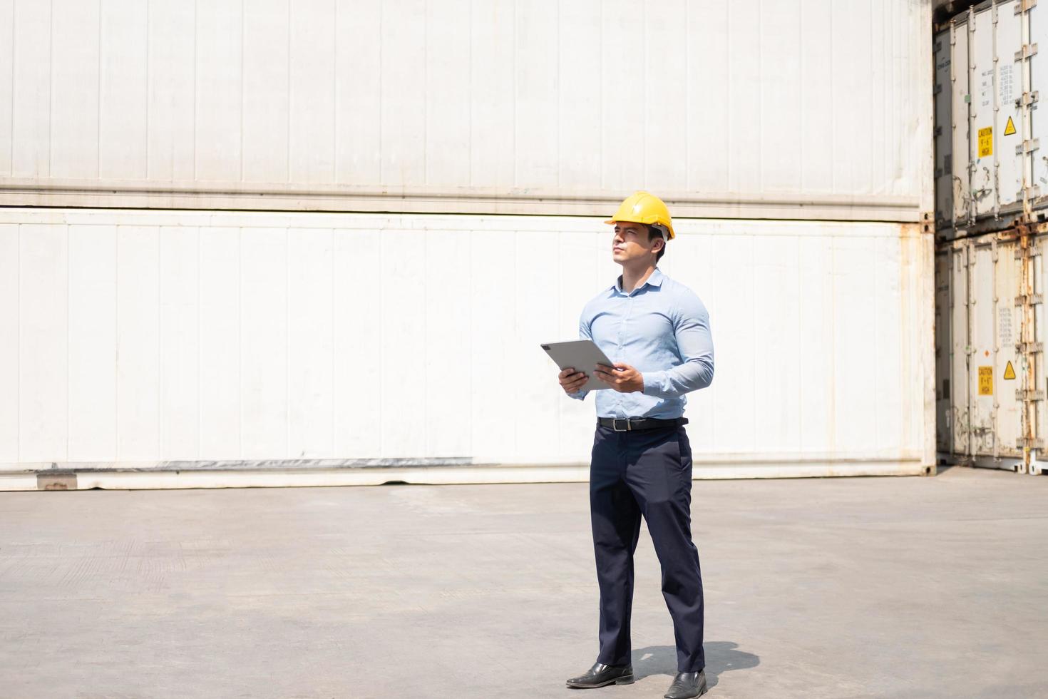 Caucasian men freight supervisor inspect the condition of all containers shipment by using tablet to record data and taking on smartphone. People and worker in freight deliver, import and export. photo
