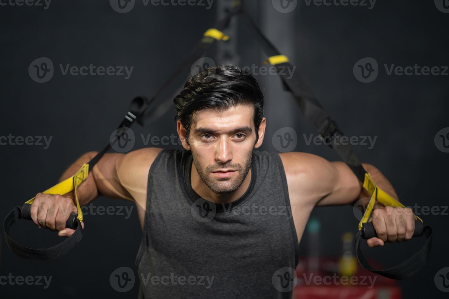 Handsome adult Caucasian men push up with sport rope to do Crossfit exercise inside of fitness gym to workout for body strength and firm arms muscle and good physical body health. photo