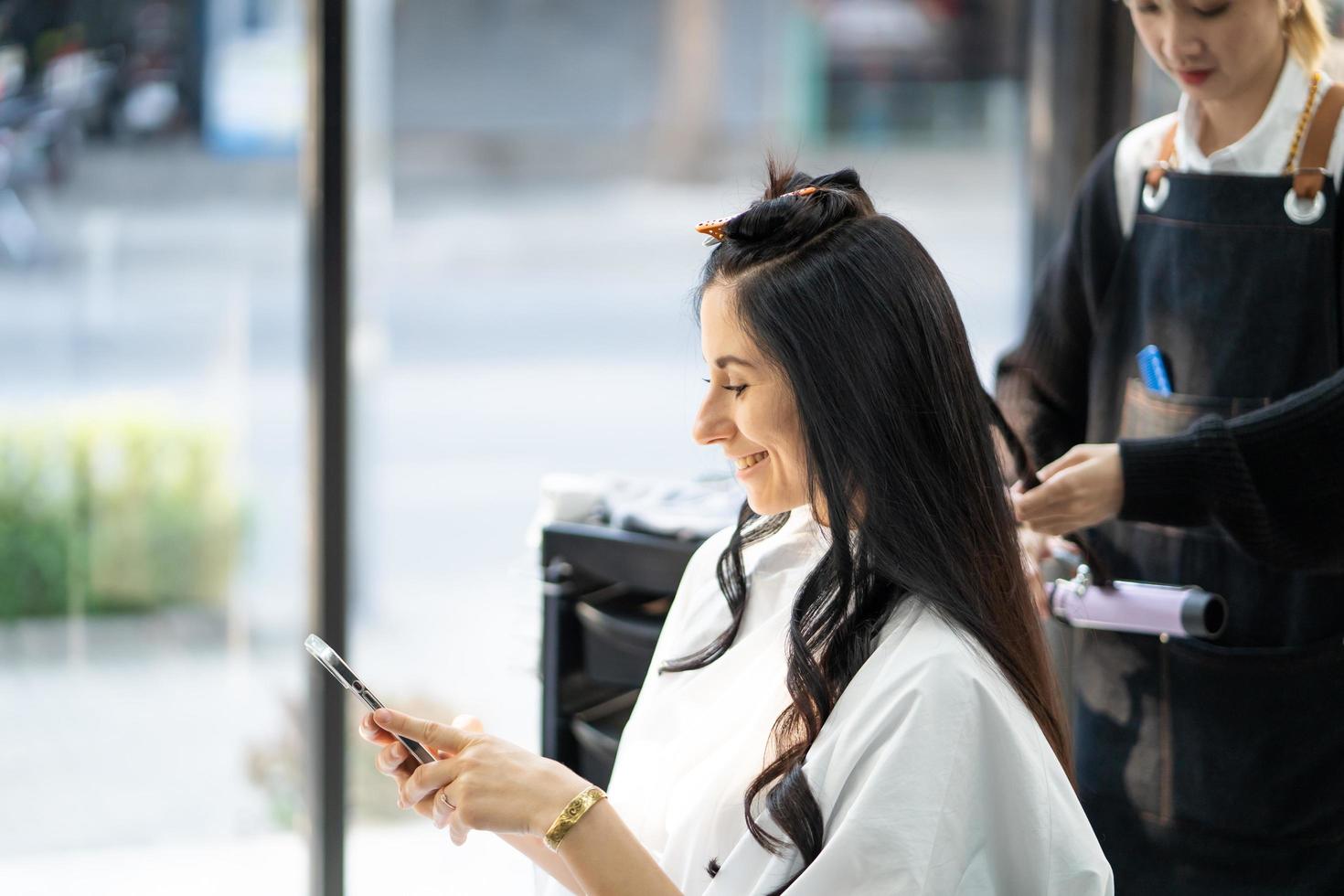 Caucasian women smile and happy with Hair stylish while do hair cut and wearing surgical face mask while styling hair for client. Professional occupation, beauty and fashion service new normal photo