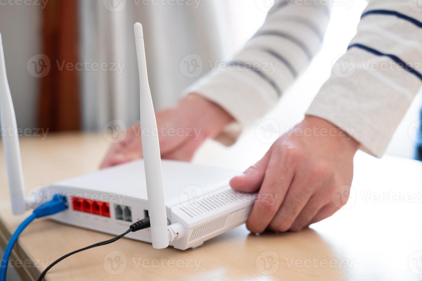 Men hands set up and install broadband high speed internet Wifi router on working table at home. With blue fiber connection line. Telecommunications and digital network technology photo