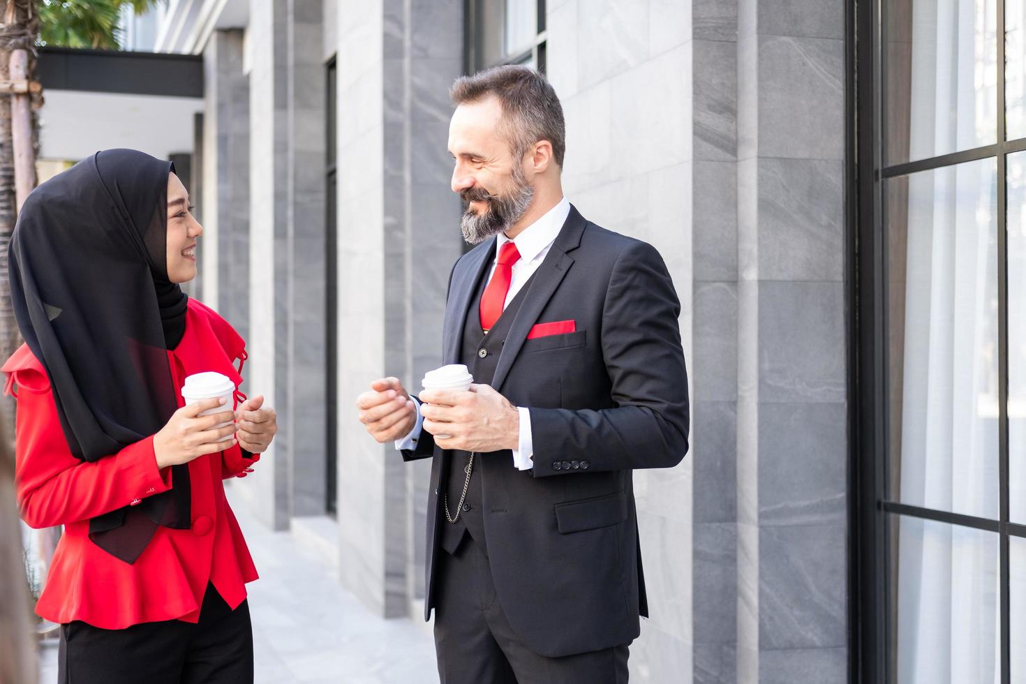 Selective focus at men face. Outdoor shot of Smart Business man and women in formal suit holding coffee cup while standing at Central Business district in the. Diverse people working environment. photo