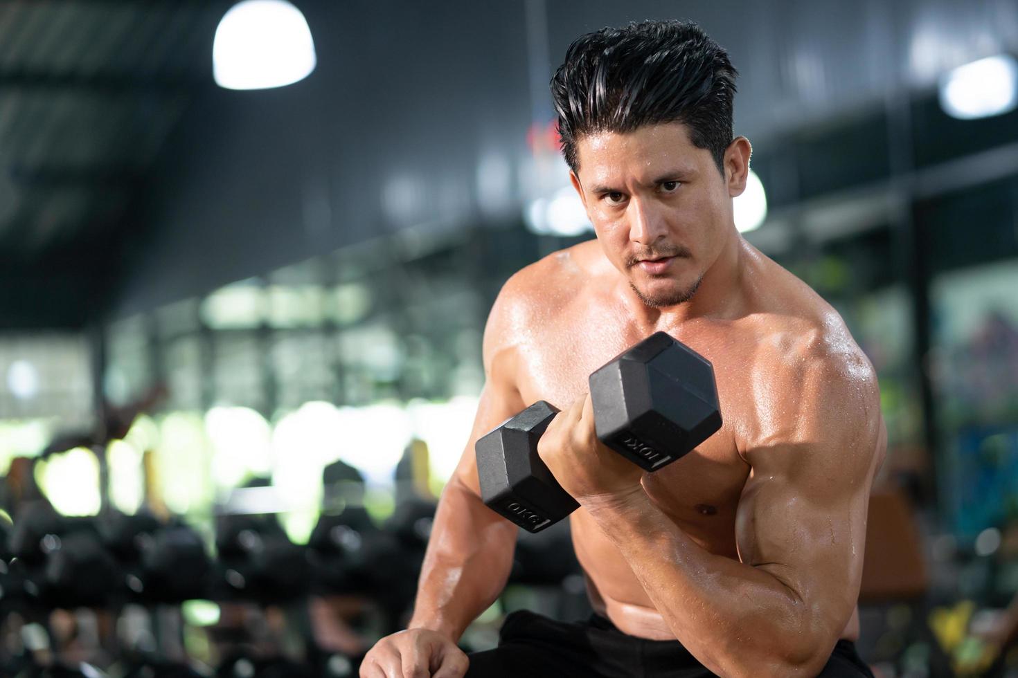 hombres caucásicos adultos guapos sudando mientras levantan el entrenamiento con mancuernas para la parte del músculo bíceps del brazo dentro del gimnasio. atleta de culturismo entrenamiento deportivo para la fuerza corporal y la buena salud. foto