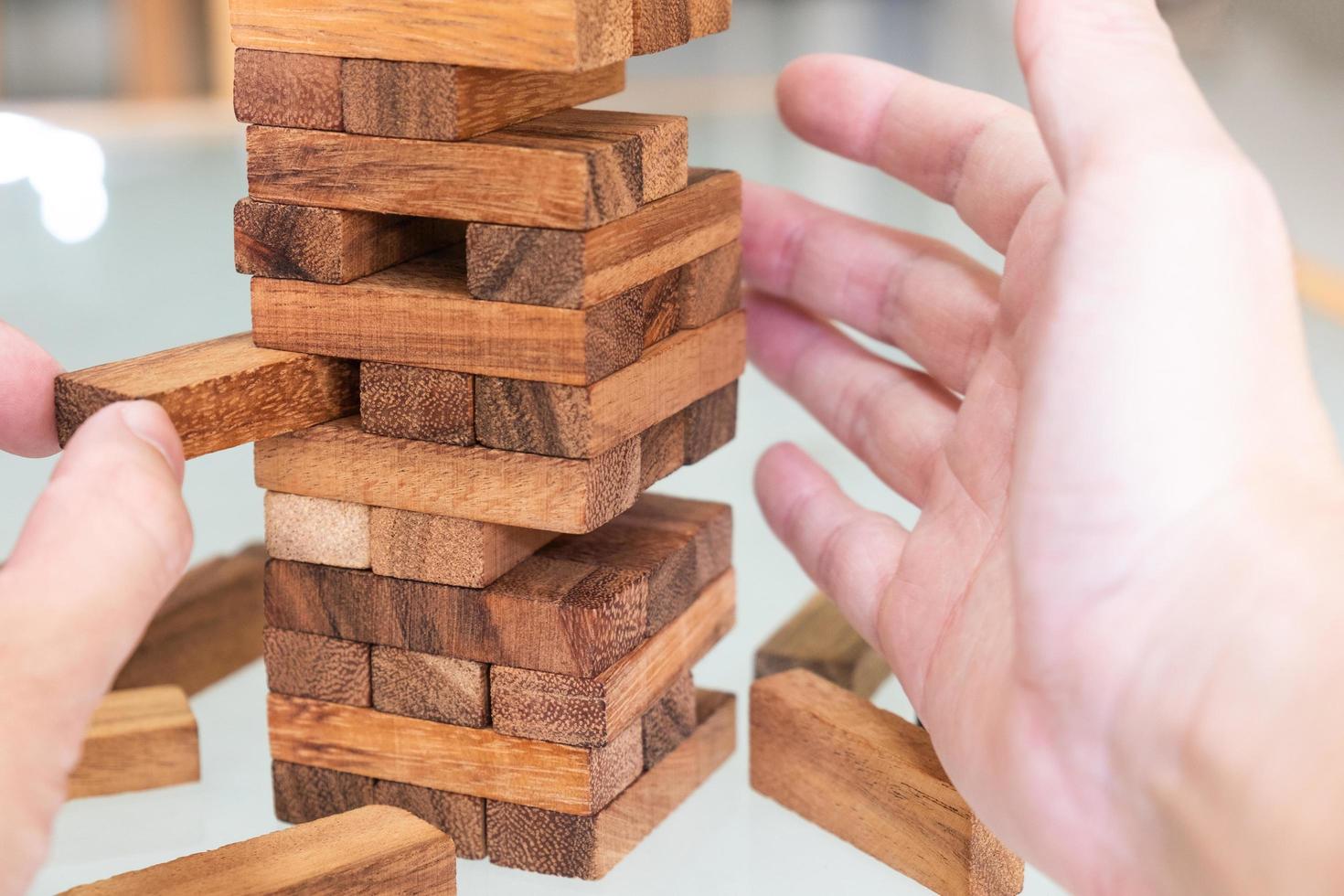 Selective focus at wood brick. Business people using hand to pull out wood brick with caution. taking risk and make decision to play the game. Insurance or financial risk management and safety concept photo