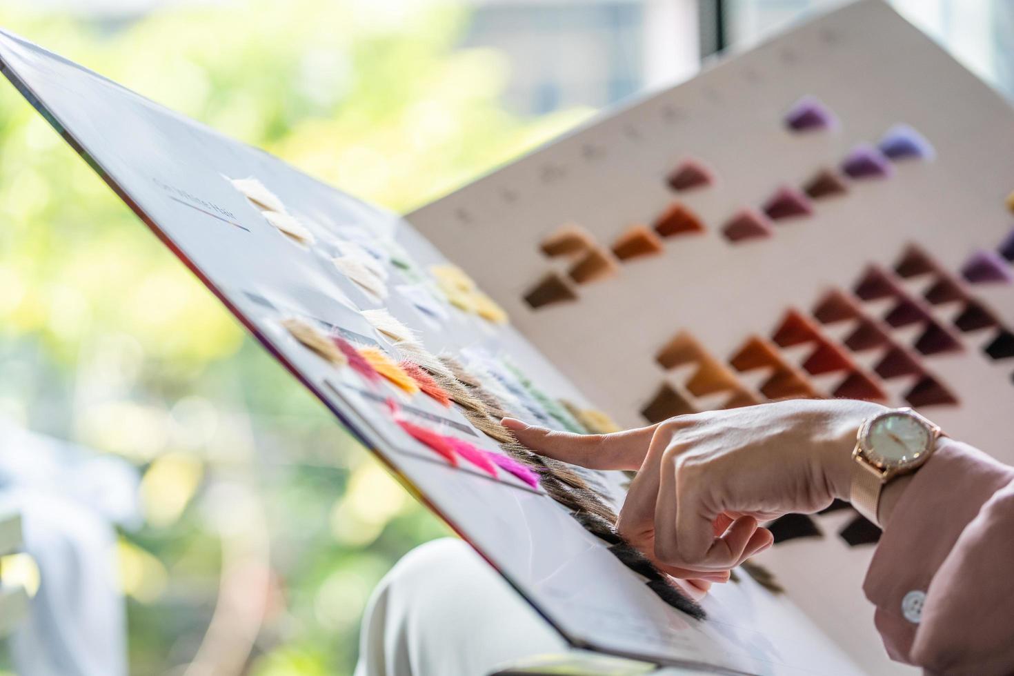 Focus at color chart. Young pretty Asian women sitting inside hair salon, smiling while choose new hair dye color and style from the color chart selection. Female beauty fashion, personal care concept photo