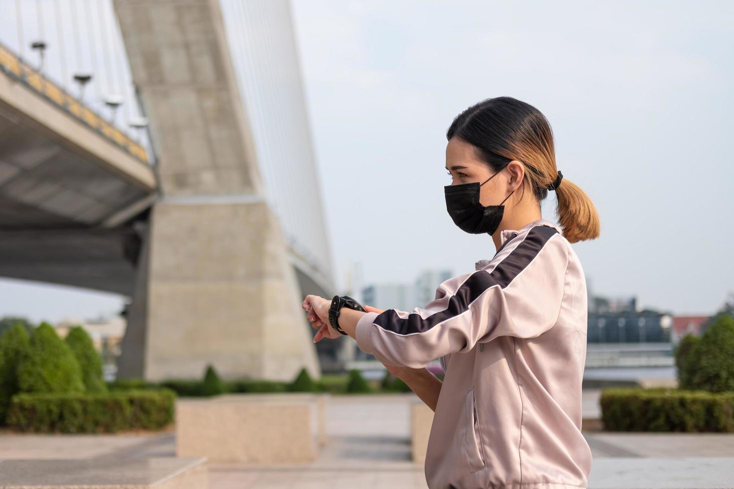 Selective focus at face of young beautiful Asian women wearing surgical face mask while stretching warm up before exercise or running at the park in the morning. New normal lifestyle. photo