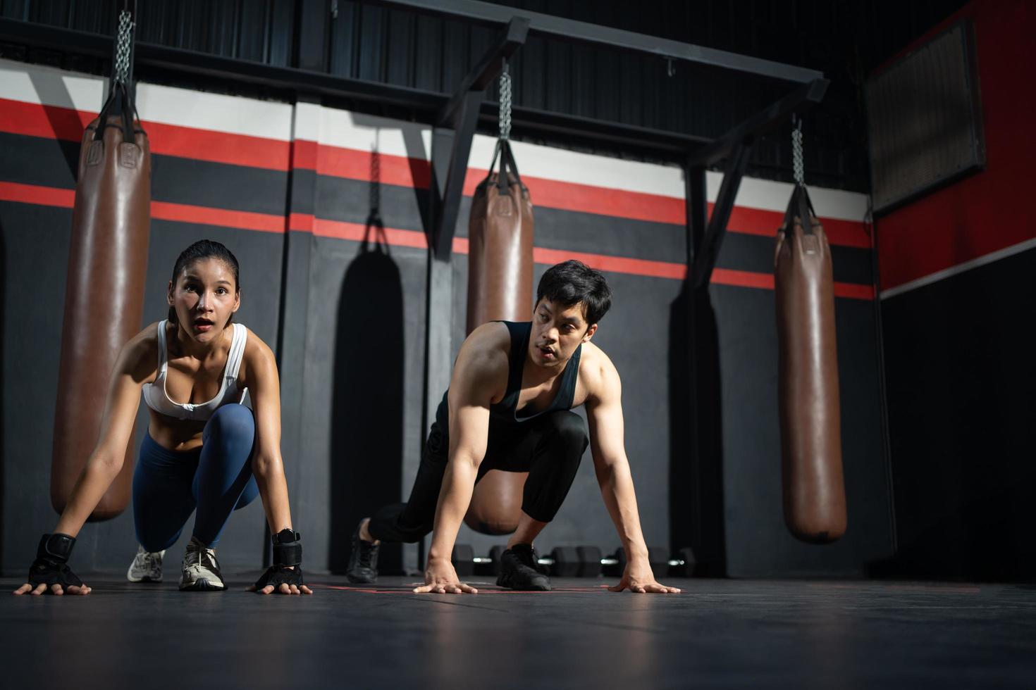 las mujeres asiáticas adultas empujan hacia arriba y se calientan con entrenadores personales masculinos antes de la clase de entrenamiento de boxeadores, el deporte, el fitness y el concepto de ejercicio para una buena salud y músculos y cuerpos fuertes. foto