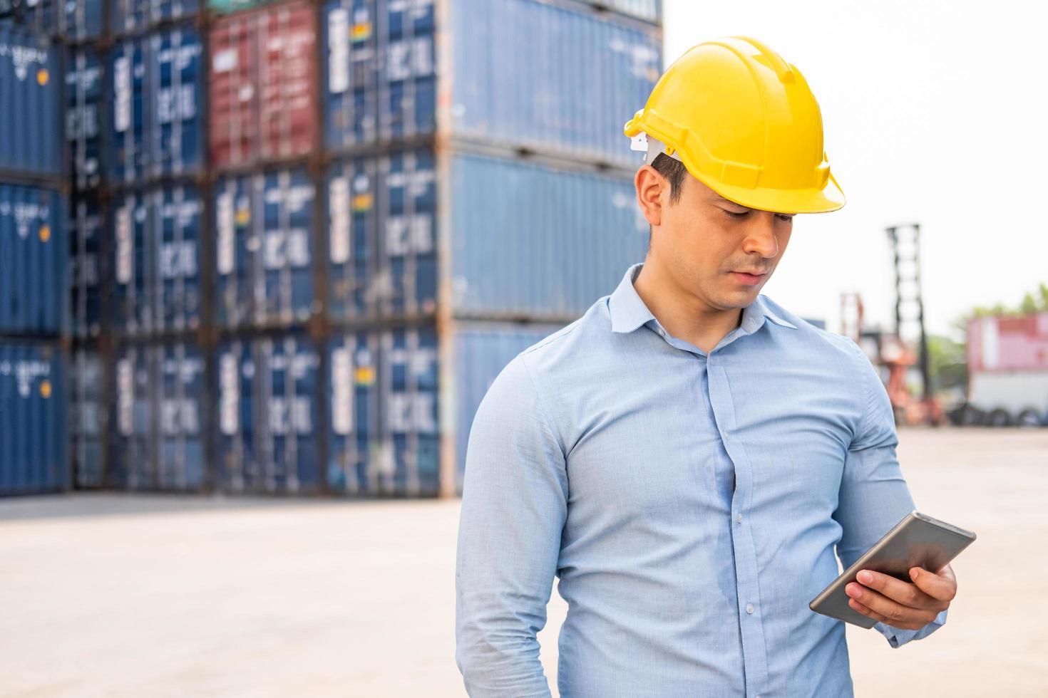 Caucasian men freight supervisor inspect the condition of all containers shipment by using tablet to record data and taking on smartphone. People and worker in freight deliver, import and export. photo