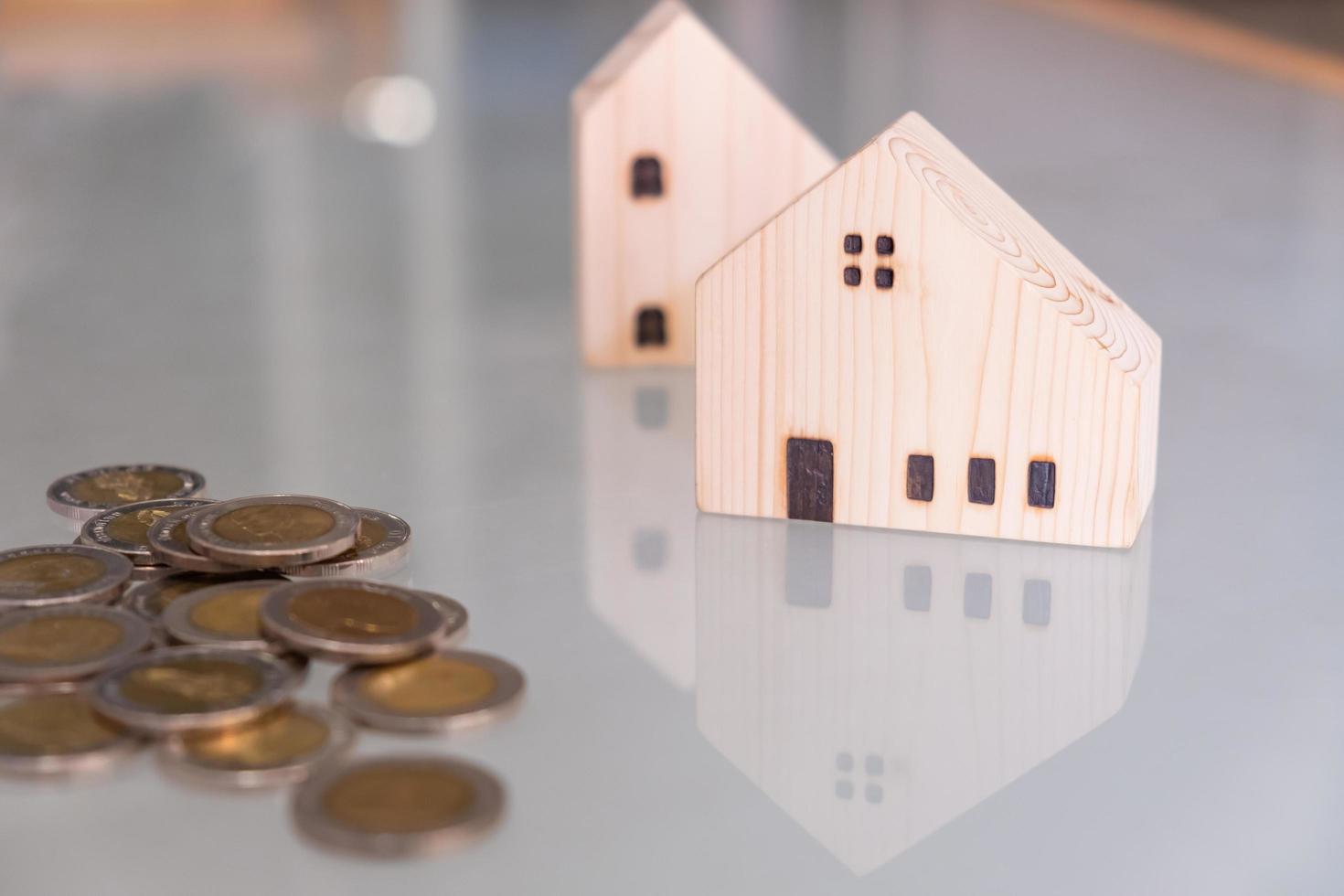 Selective focus at wooden house mock up that put on the top of growth money coins stack on the glass table with blurred background. Wealth and saving for home ownership and financial concept. photo