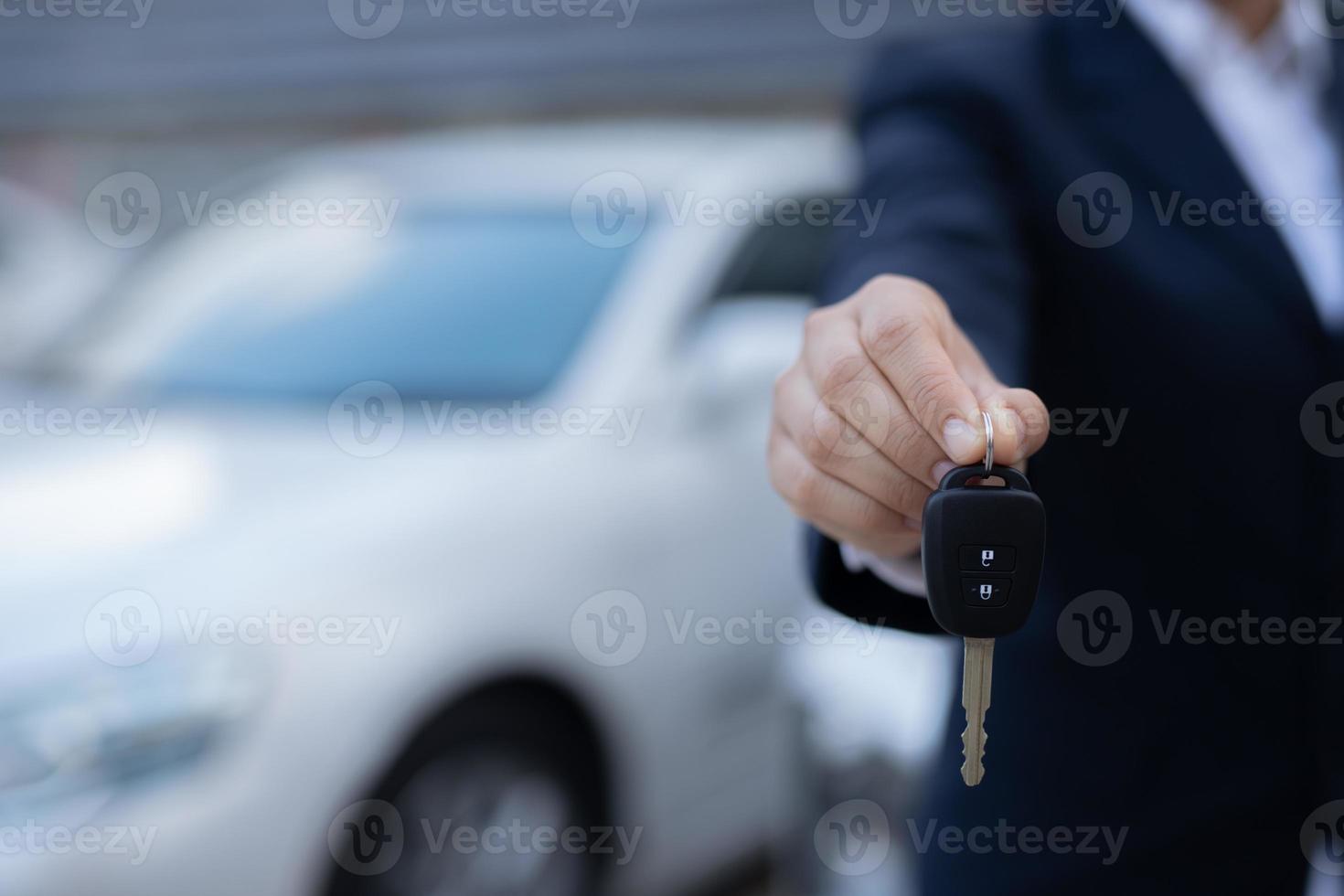 Salesman is carrying the car keys delivered to the customer at the showroom with a low interest offer. Special promotion photo