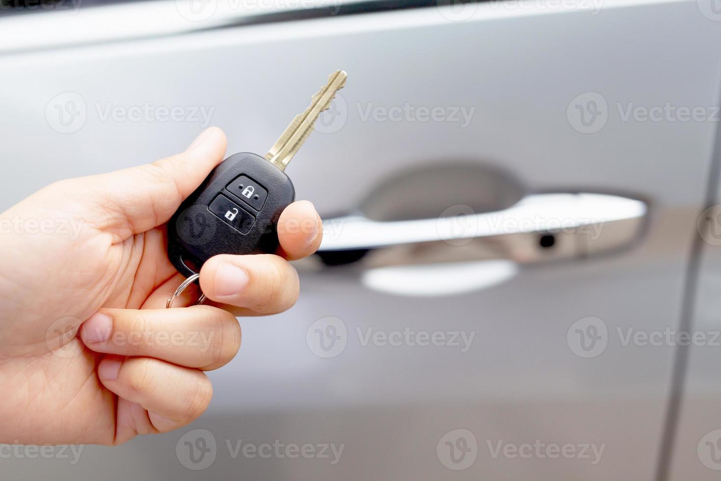A man holding a car key in front of a car at a showroom photo