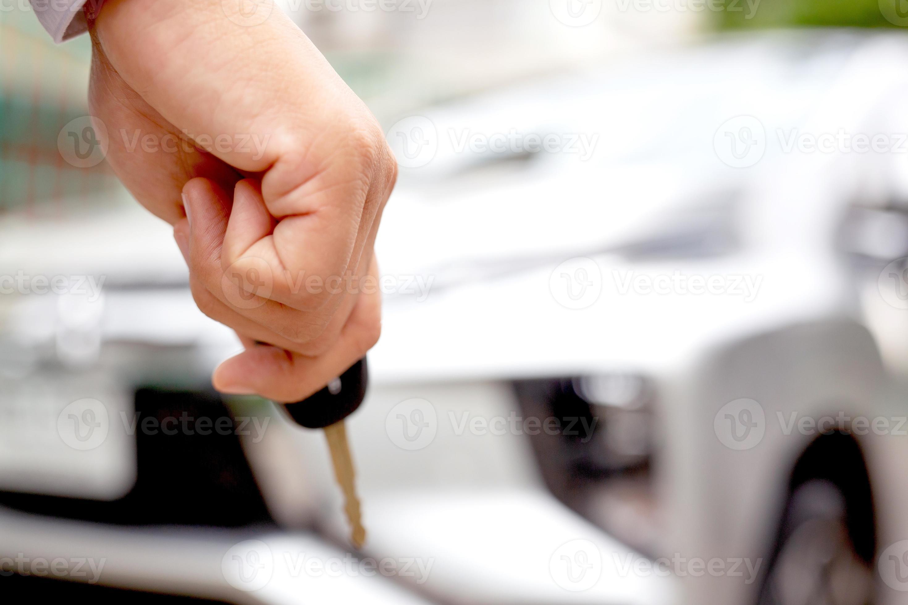 A man holding a car key in front of a car at a showroom 13000852 Stock