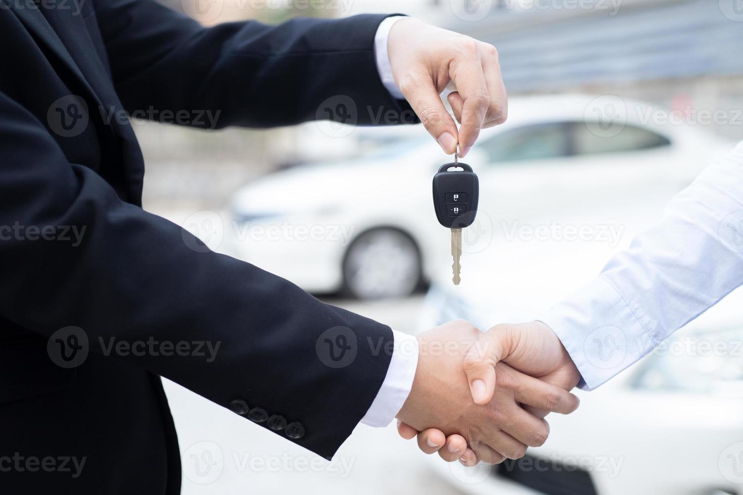 el vendedor lleva las llaves del auto entregadas al cliente en la sala de exposición con una oferta de bajo interés. promoción especial foto