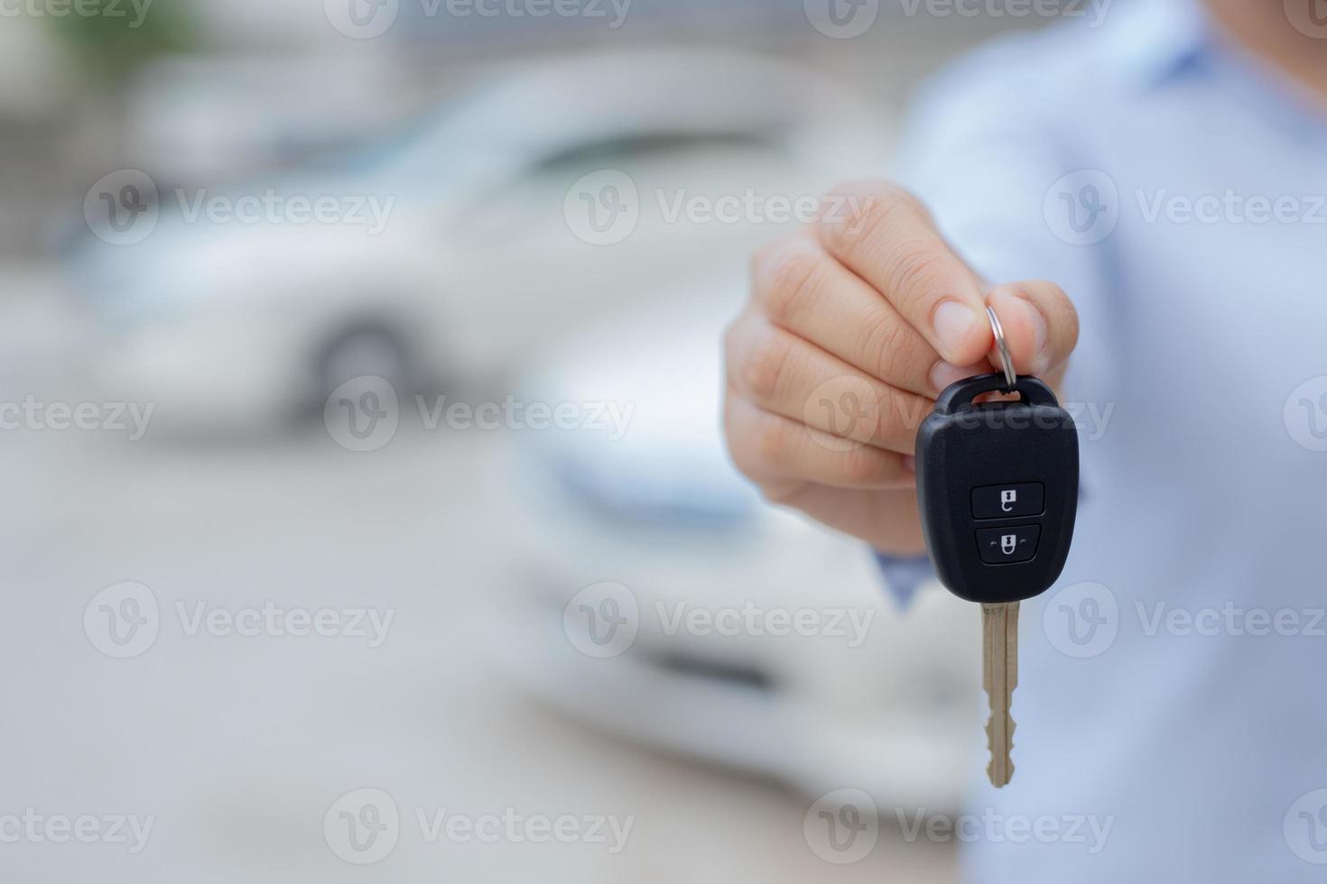 Salesman is carrying the car keys delivered to the customer at the showroom with a low interest offer. Special promotion photo