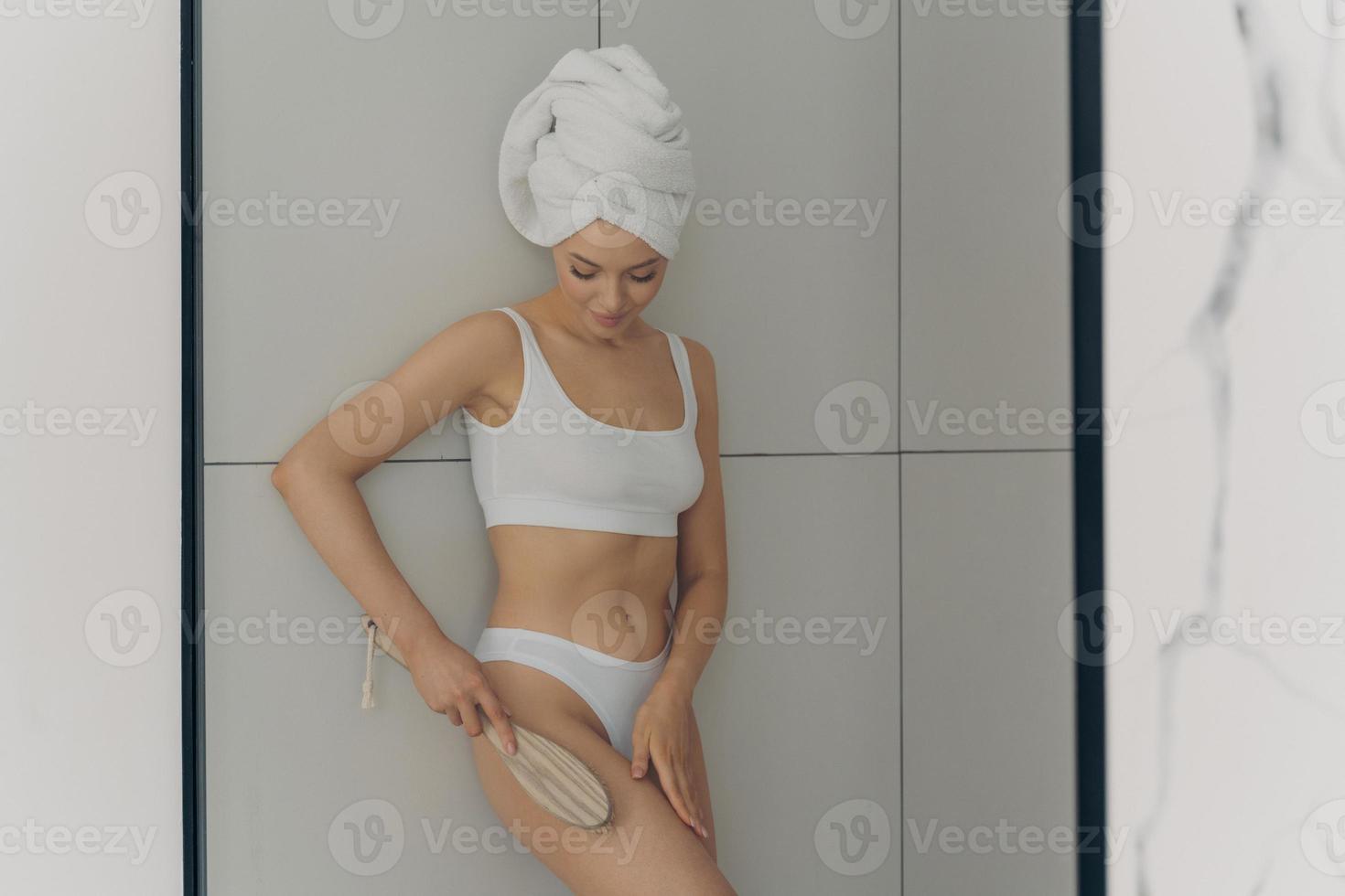 Photo of young beautiful woman wears classic lingerie doing body massage with brush
