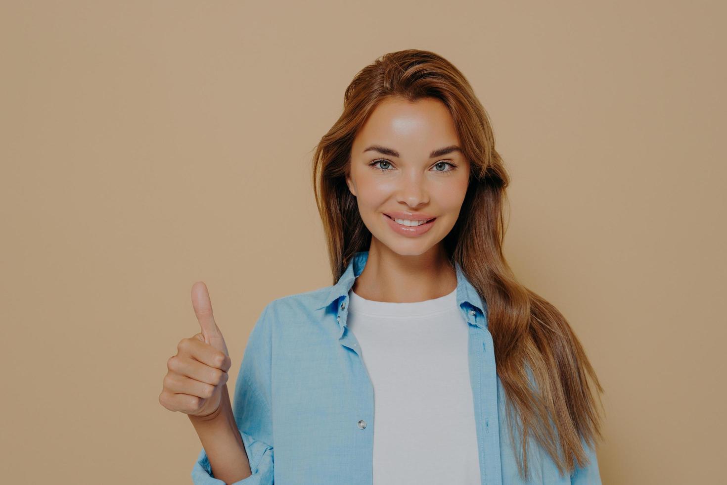Waist up shot of satisfied supportive woman shows thumb up photo
