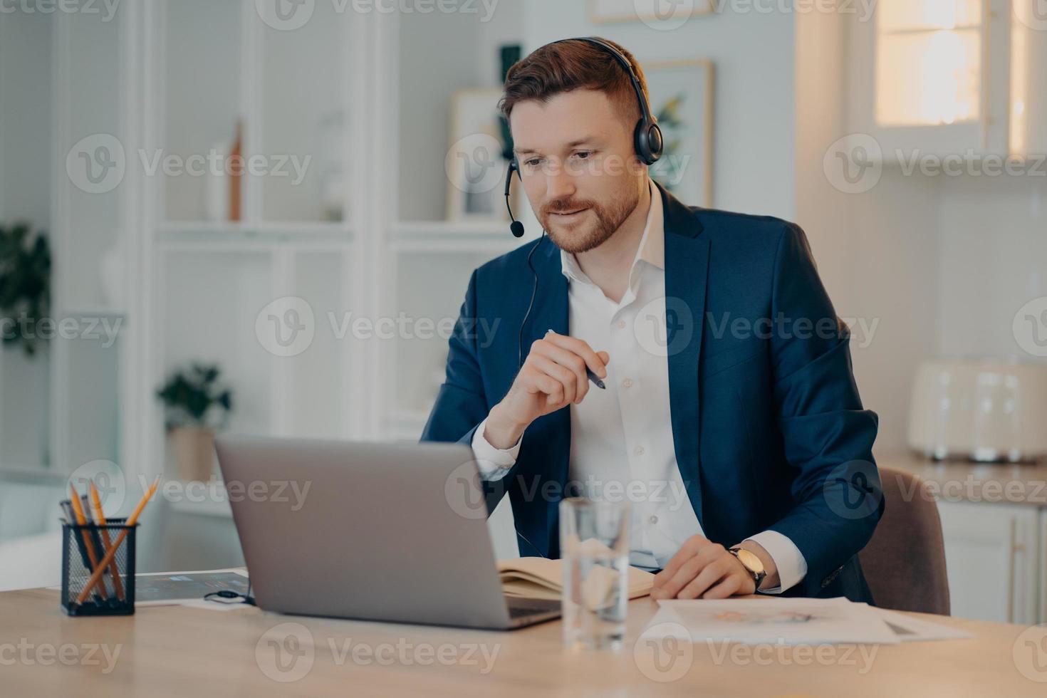 un hombre de negocios sonriente hablando con su socio de negocios mientras usa una videollamada en una laptop foto