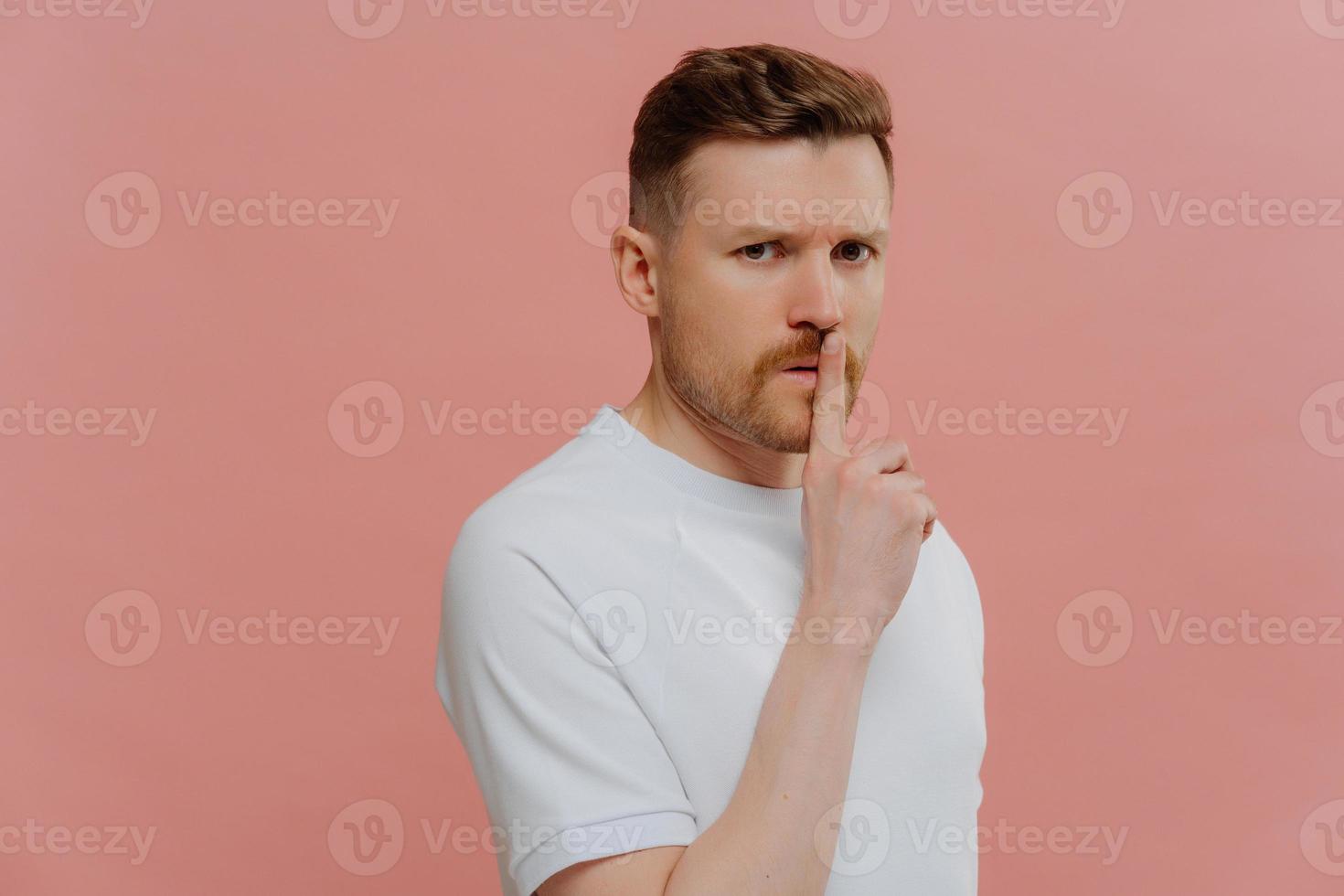 Young unshaven mysterious man in white shirt asking to keep information in secret photo