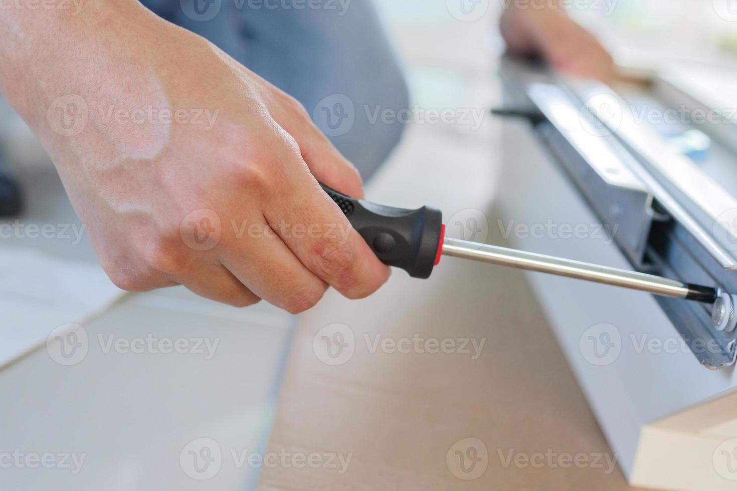 Asian man assembling white table furniture at home photo
