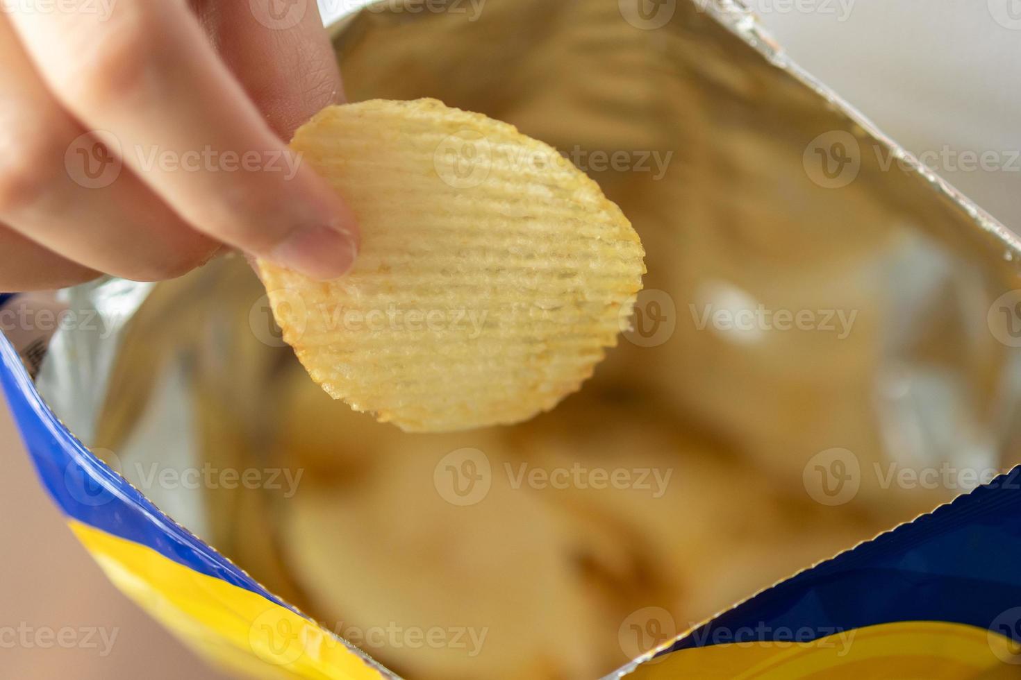 Hand hold potato chips with snack bag photo