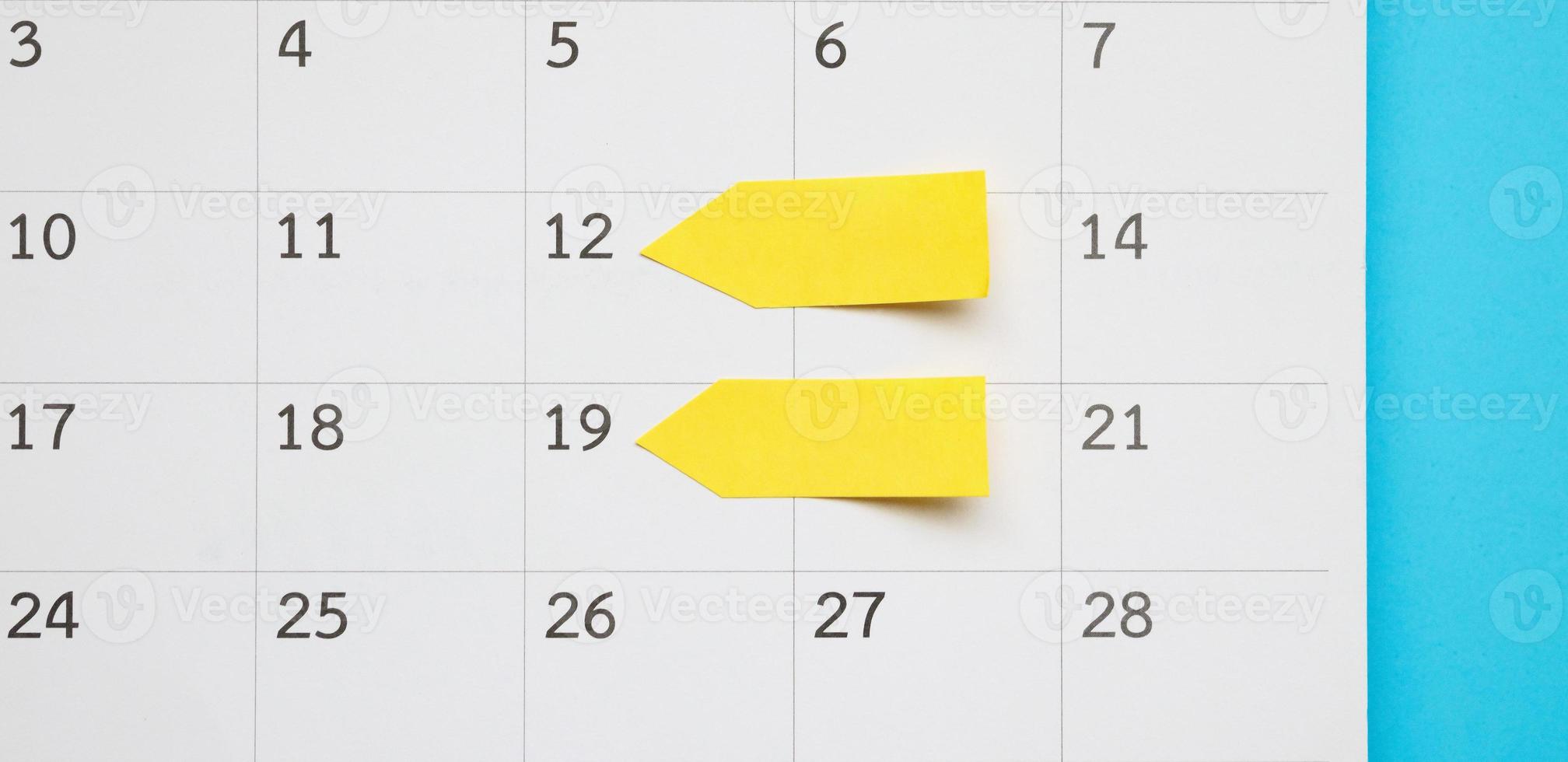 Blank yellow sticky adhesive post note paper planner with space on calendar page background for business planning appointment meeting concept photo