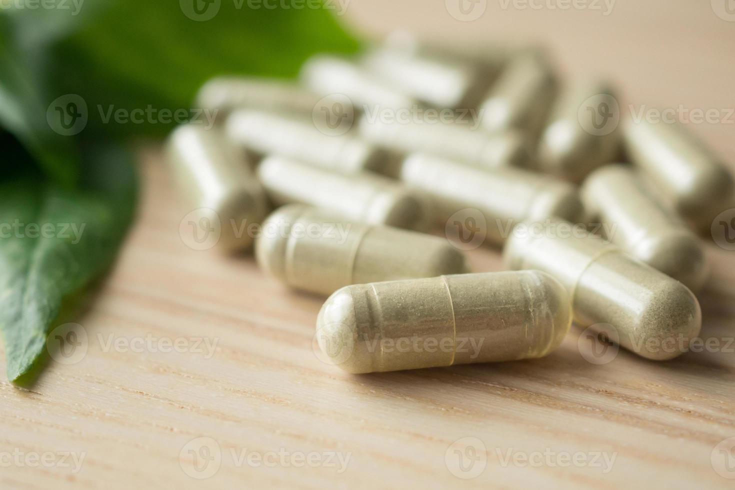 Herbal medicine capsules with Andrographis paniculata leaf on wood table photo