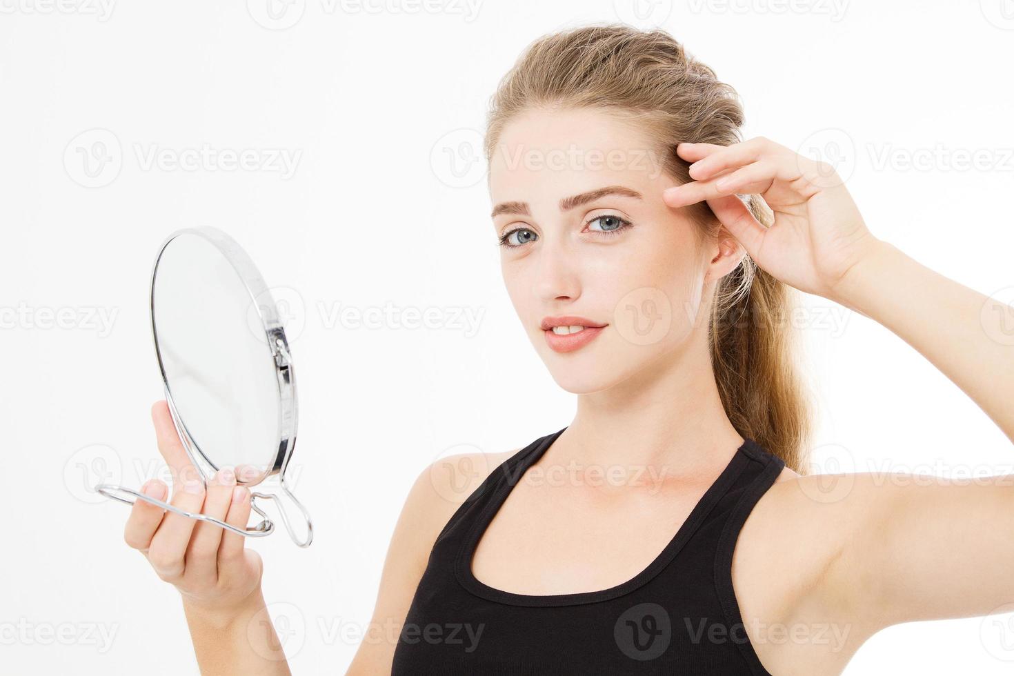 Young caucasian blonde woman looking wrinkles on face in mirror isolated on white background. Skin care and makeup concept. Copy space photo